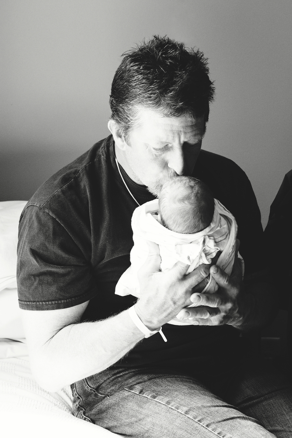 A dad kisses his newborn baby boy in the hospital during a fresh 48 session