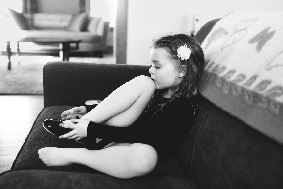 a young girl wearing dance clothes puts on her shoes